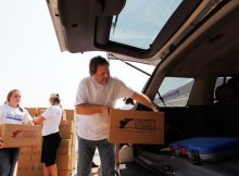 EULESS, TX - AUGUST 03: Texas Motor Speedway President Eddie Gossage helps to load a vehicle with a 25-pound box of non-perishable food, 10-pound box of personal supplies and box of AVON products to one of 800 families in need from the Mid-Cities area (Hurst, Euless, Bedford) at the 6 Stones Mission Network on August 3, 2011 in Euless, Texas. The event was the first of Texas Motor Speedway's month-long "Speeding To Help" community outreach program. (Photo by Tom Pennington/Getty Images for TMS)